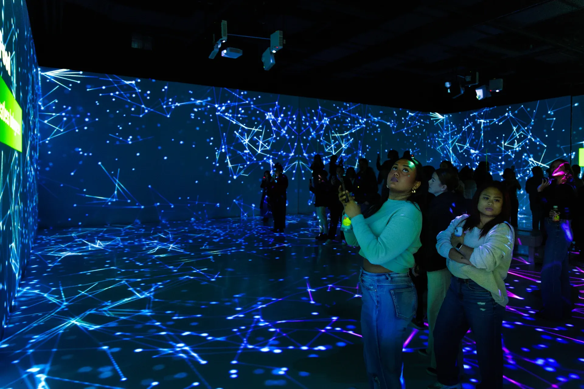 People in a projection room, dark and lit up on the walls, grid pattern blue